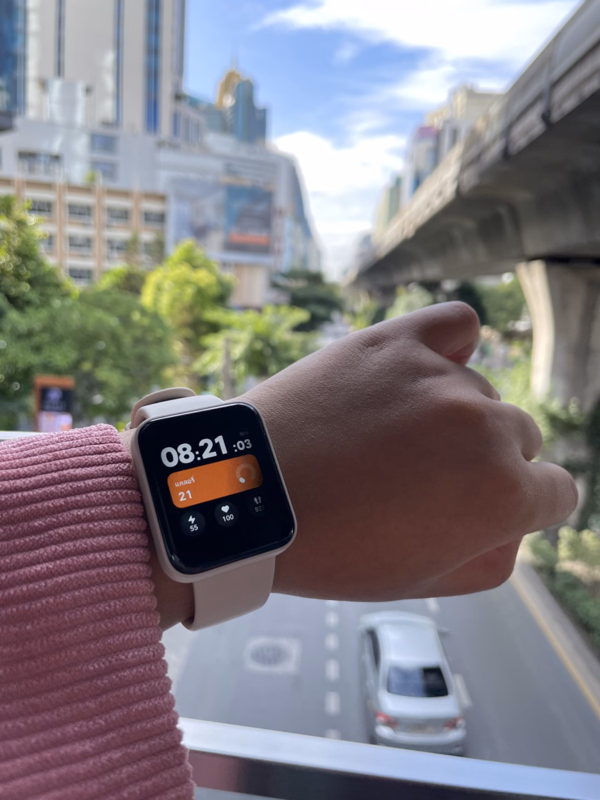 Study shows that smartwatches loose up to 60% of their value in less than 6 months 1 A close-up of a smartwatch displaying the time as 08:21:03 along with health metrics, set against a blurred background of a city street with buildings and trees.