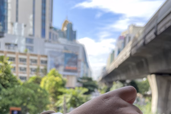 A close-up of a smartwatch displaying the time as 08:21:03 along with health metrics, set against a blurred background of a city street with buildings and trees.
